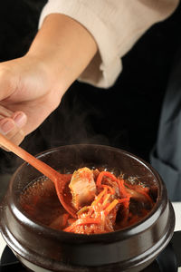 Female hand cooking kimchi stew soup or kimchi jigae, korean traditional food 