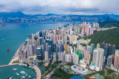 High angle view of city by sea and buildings against sky