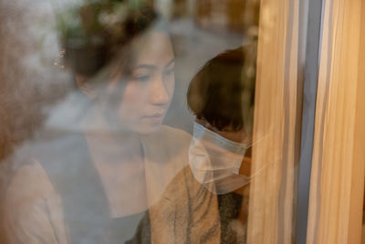 Portrait of woman looking through window