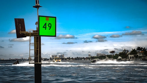 Information sign by sea against blue sky