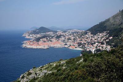 Aerial view of townscape by sea against sky