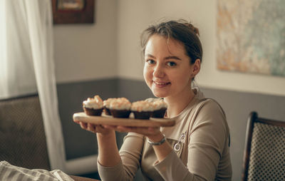 Young woman shows cupcakes in her hand. cream decoration. the bakery chef bakes cakes in the kitchen