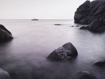 Rock formation in sea against clear sky