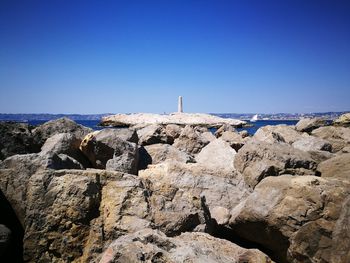 Rock formations in sea against clear blue sky