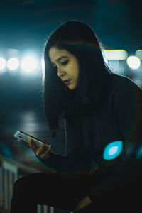 Young woman holding camera at night