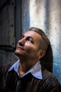 Portrait of mature man looking away against wall