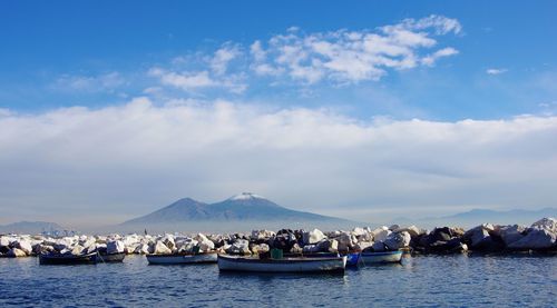 Boats moored in sea with mountain range in background