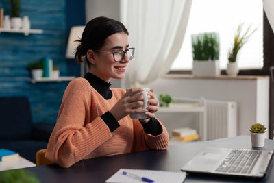 Smiling businesswoman holding coffee cup sitting at office