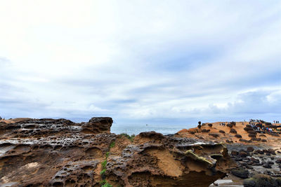 Rock formations on beach against sky