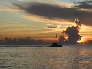 Silhouette sailboats in sea against sky during sunset