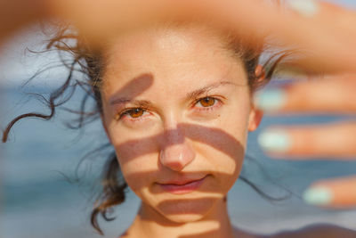 Close-up portrait of young woman with hand over face