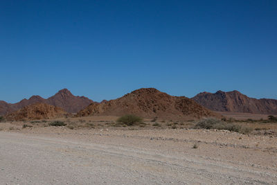 Scenic view of desert against clear blue sky