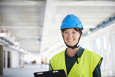 Portrait of smiling female construction manager in reflective clothing at site