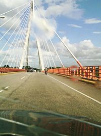 Suspension bridge against cloudy sky