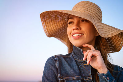 Portrait of smiling young woman against clear sky