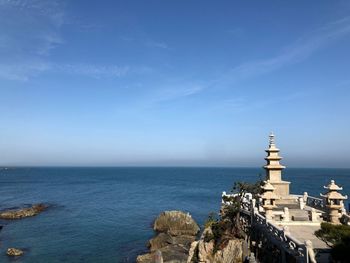 Scenic view of sea by building against blue sky