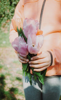 Midsection of girl holding tulips while standing on land