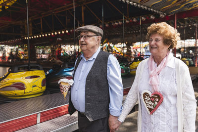 Happy senior couple walking hand in hand on fair