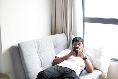 Man using mobile phone while sitting on sofa at home