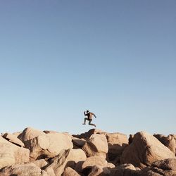 Man riding horse on rock against clear sky