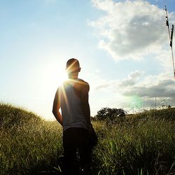 Rear view of man standing on field against sky