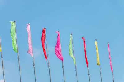 Low angle view of colorful flags against clear blue sky