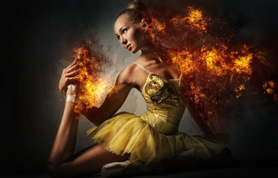 Digital composite image of dancing woman burning in fire against black background