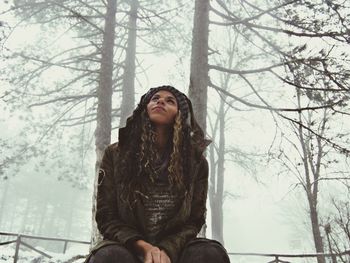 Woman sitting at forest during winter