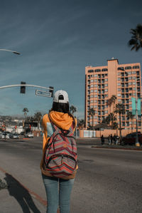 Rear view of woman standing on road in city
