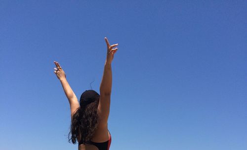 Low angle view of woman against clear blue sky