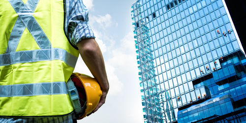 Low angle view of man standing by building against sky