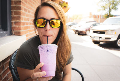 Portrait of woman holding ice cream in city