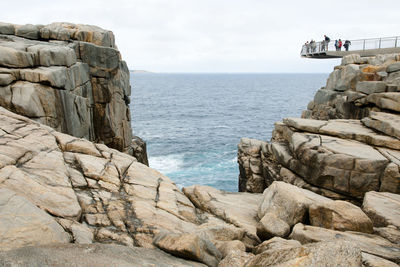 Scenic view of rocks by sea against sky