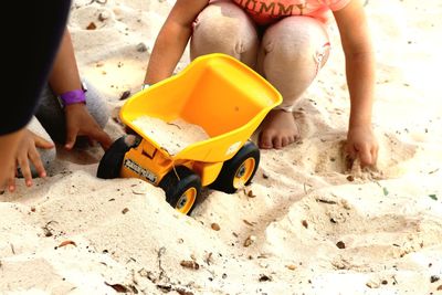 Children with toy wheelbarrow playing on sand