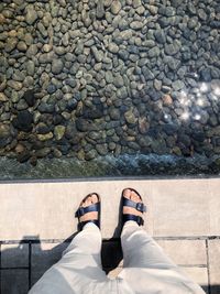 Low section of man standing on pebbles