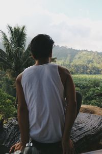 Rear view of man sitting on wood