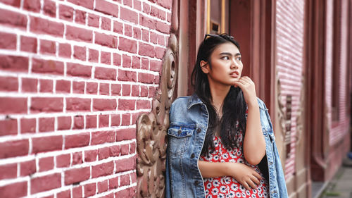 Portrait of woman standing against brick wall