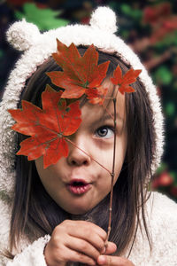 Close-up portrait of young woman with autumn leaves