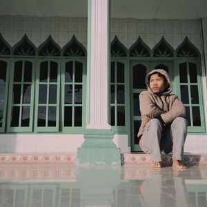 Full length of thoughtful man sitting outside mosque