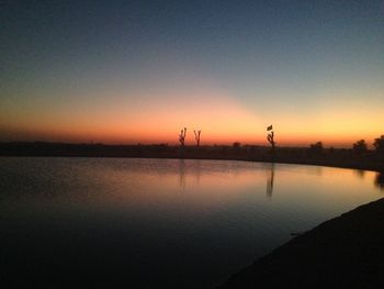 Scenic view of lake against clear sky during sunset