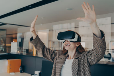 Cheerful woman using virtual reality simulator at home