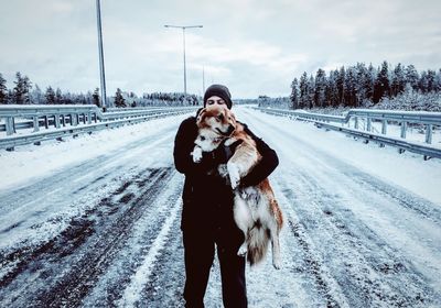 Full length of man standing on snow with dog