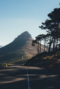 Scenic view of road by mountains against clear sky