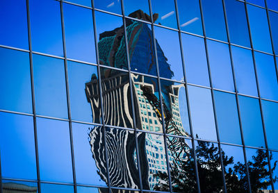 Low angle view of glass building against blue sky