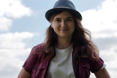 Portrait of young woman standing against sky