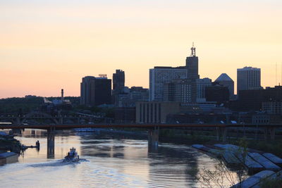 Bridge over river by city during sunset