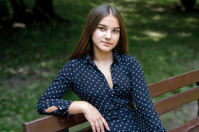 Portrait of young woman sitting against trees