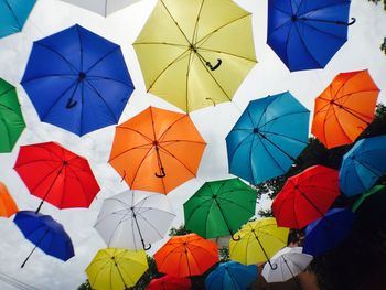 Low angle view of umbrellas hanging against blue sky