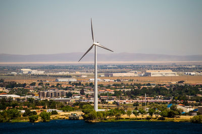 Wind turbines in city against clear sky