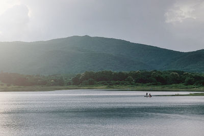 Scenic view of lake by mountains against sky